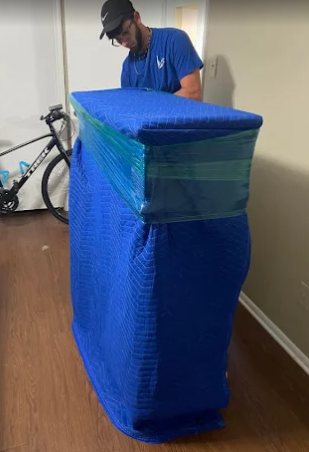 Tall furniture item wrapped in protective blue padding